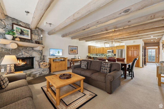 living area featuring a stone fireplace, beamed ceiling, and light carpet
