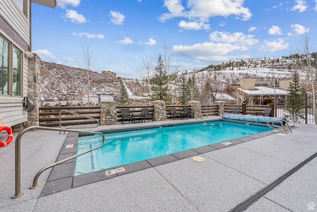 snow covered pool featuring a mountain view and a patio