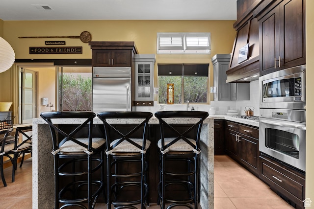 2139 W Cougar Rock Cir S Unit 135, St George, UT 84770 - kitchen featuring built in appliances, a kitchen breakfast bar, dark brown cabinetry, and light tile patterned flooring