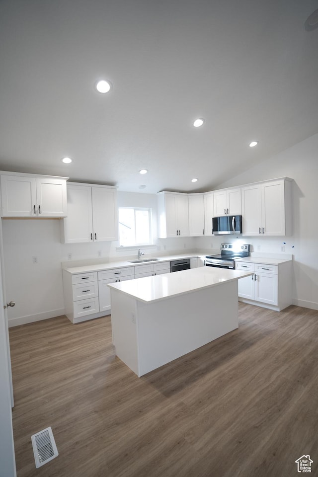 2277 E 3530 N Unit 511, Eagle Mountain, UT 84005 - kitchen with visible vents, a kitchen island, a sink, white cabinets, and appliances with stainless steel finishes