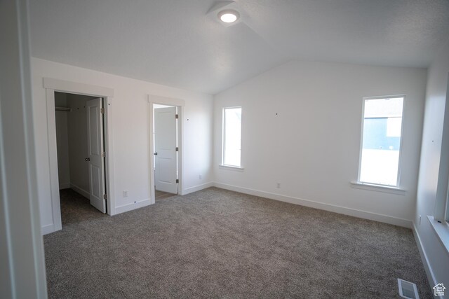 2277 E 3530 N Unit 511, Eagle Mountain, UT 84005 - unfurnished bedroom with baseboards, visible vents, carpet floors, lofted ceiling, and a walk in closet