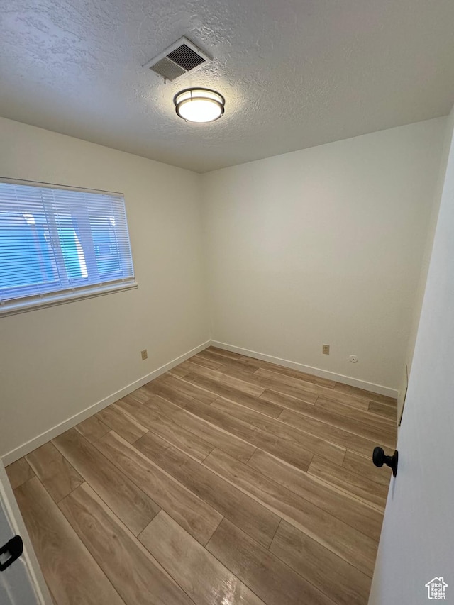 5630 S Meadow Ln Unit 197, South Ogden, UT 84403 - spare room with baseboards, light wood-style floors, a textured ceiling, and visible vents