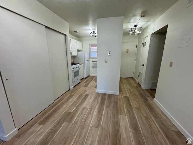 5630 S Meadow Ln Unit 197, South Ogden, UT 84403 - kitchen featuring a wall unit AC, light wood-style flooring, white appliances, a textured ceiling, and white cabinets