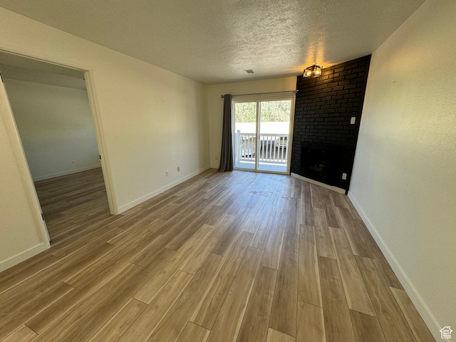 5630 S Meadow Ln Unit 197, South Ogden, UT 84403 - empty room featuring a textured ceiling, baseboards, a fireplace, and wood finished floors