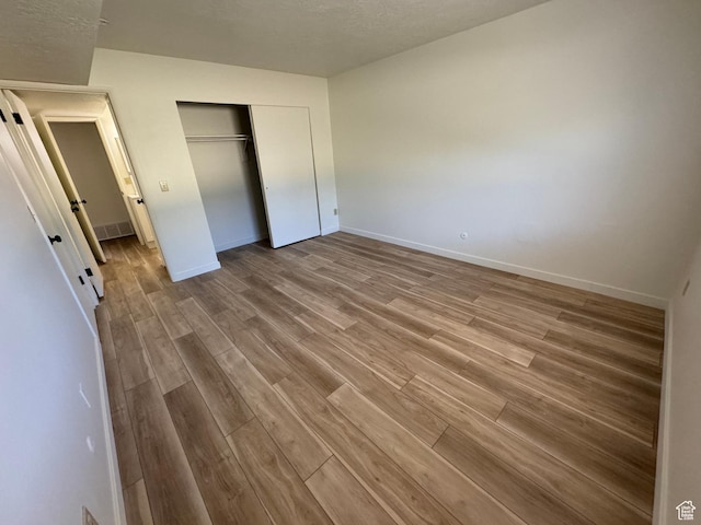 5630 S Meadow Ln Unit 197, South Ogden, UT 84403 - unfurnished bedroom with a closet, a textured ceiling, visible vents, baseboards, and wood finished floors