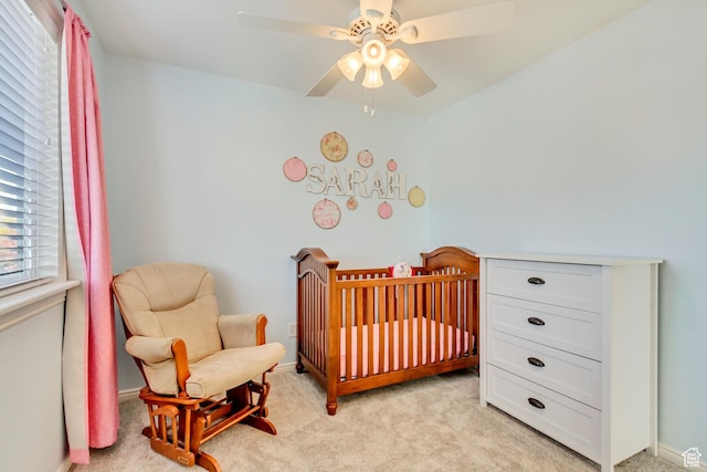bedroom with light colored carpet, baseboards, a ceiling fan, and a crib