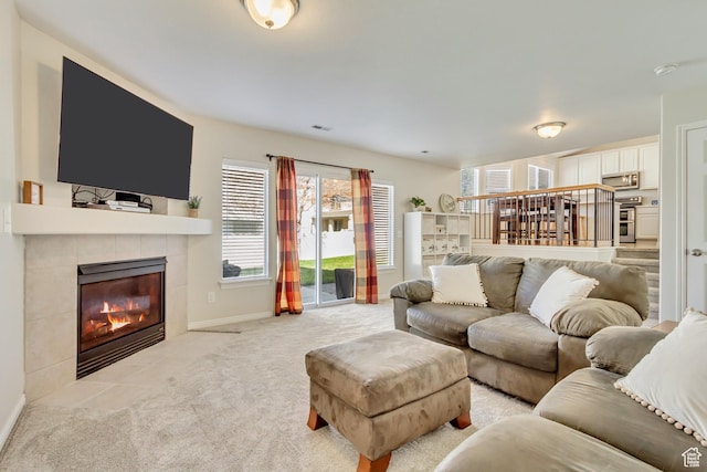 living room with light carpet, a tile fireplace, visible vents, and baseboards