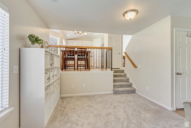 interior space featuring stairway, carpet flooring, baseboards, and a notable chandelier