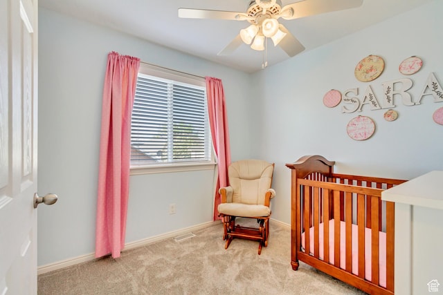 carpeted bedroom featuring a ceiling fan, baseboards, and a nursery area