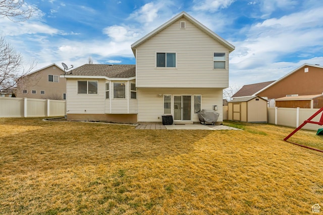 rear view of property featuring a storage unit, an outbuilding, a fenced backyard, a patio area, and a yard