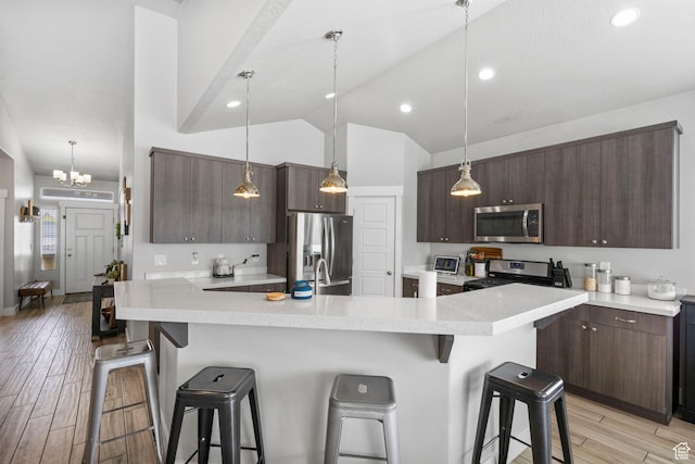 5131 N Stratford Dr W, Stansbury Park, UT 84074 - kitchen with a breakfast bar area, dark brown cabinetry, and appliances with stainless steel finishes