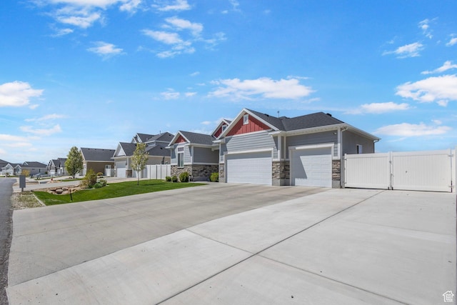 5131 N Stratford Dr W, Stansbury Park, UT 84074 - view of front of house with fence, a residential view, concrete driveway, stone siding, and a garage