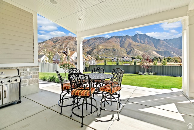 view of patio featuring outdoor dining area, a fenced backyard, a mountain view, and grilling area