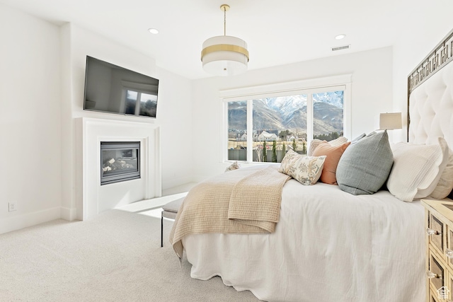 carpeted bedroom featuring a glass covered fireplace, recessed lighting, baseboards, and visible vents