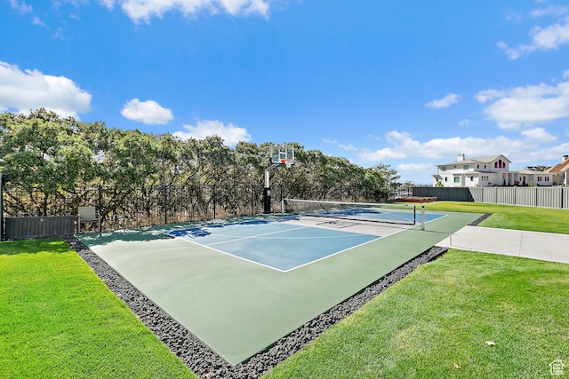 view of sport court featuring a tennis court, a lawn, and fence