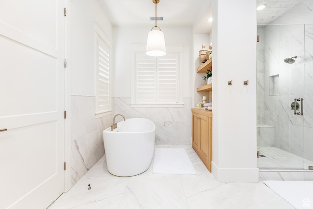 full bathroom with vanity, visible vents, a marble finish shower, a freestanding bath, and tile walls