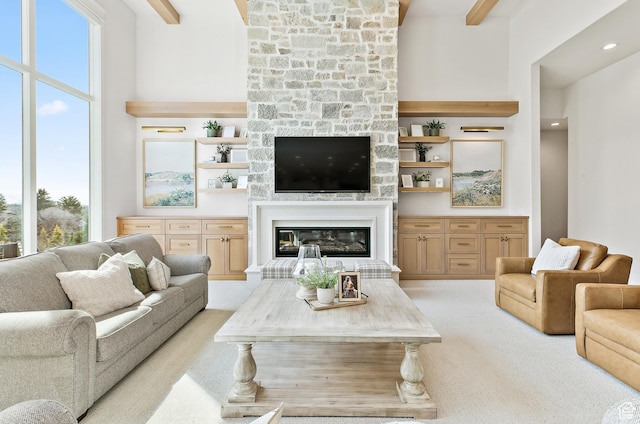 living room featuring a healthy amount of sunlight, a fireplace, a towering ceiling, and light carpet