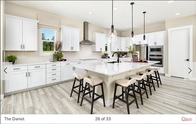 1811 N 375 W Unit 8, Harrisville, UT 84404 - kitchen with a sink, white cabinetry, appliances with stainless steel finishes, a breakfast bar area, and wall chimney exhaust hood