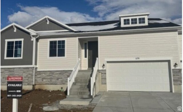 view of front of home with concrete driveway, a garage, and stone siding