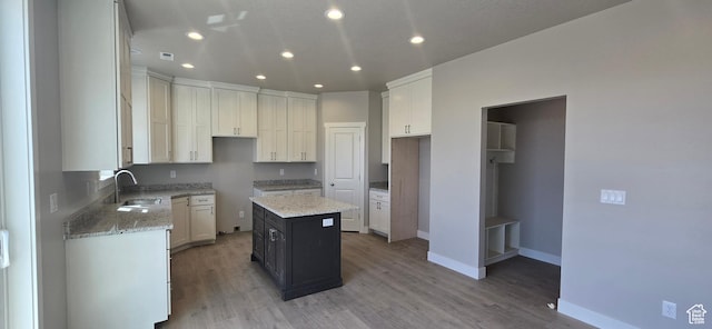kitchen featuring light wood-style floors, baseboards, light stone countertops, and a sink