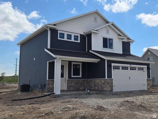 craftsman inspired home featuring covered porch, stone siding, central AC unit, and an attached garage