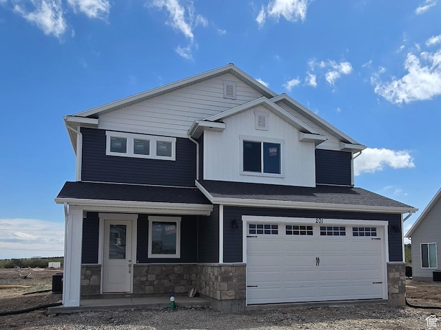 view of front of property featuring a porch, a garage, stone siding, and gravel driveway