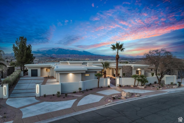 2031 E Cliff Point Dr, St George, UT 84790 - view of front of house featuring stucco siding, a fenced front yard, concrete driveway, and a mountain view
