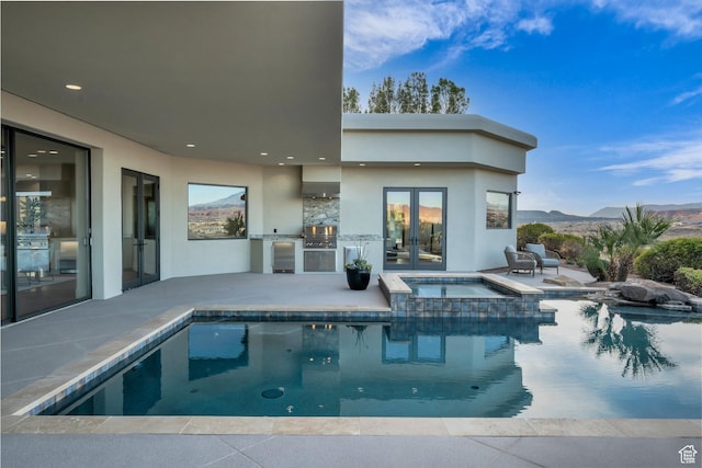 2031 E Cliff Point Dr, St George, UT 84790 - view of pool featuring a patio, an outdoor kitchen, a pool with connected hot tub, french doors, and a mountain view