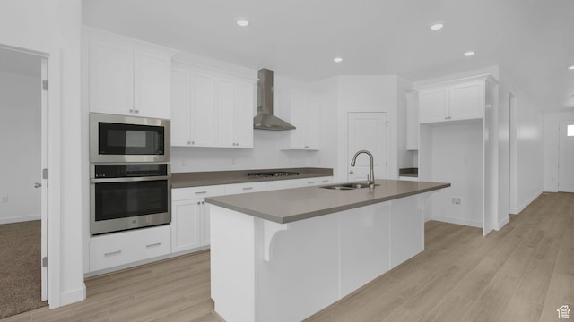 6311 W Butte County Dr S Unit 448, Herriman, UT 84096 - kitchen featuring stainless steel appliances, wall chimney range hood, a sink, a center island with sink, and white cabinetry