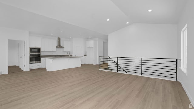 6311 W Butte County Dr S Unit 448, Herriman, UT 84096 - unfurnished living room featuring recessed lighting, vaulted ceiling, light wood-style flooring, baseboards, and a sink