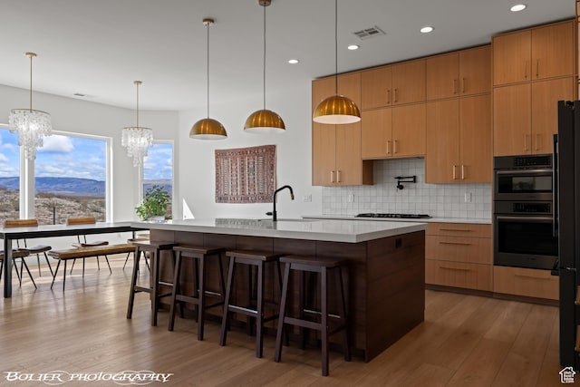 3218 E Rimrunner Dr, St George, UT 84790 - kitchen with visible vents, light wood-type flooring, a notable chandelier, backsplash, and light countertops