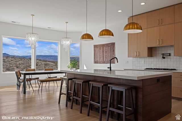 3218 E Rimrunner Dr, St George, UT 84790 - kitchen featuring a notable chandelier, gas cooktop, a mountain view, light wood finished floors, and decorative backsplash