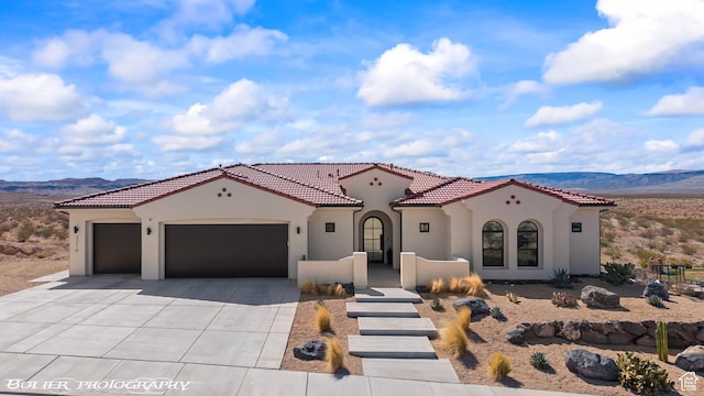 3218 E Rimrunner Dr, St George, UT 84790 - mediterranean / spanish-style house featuring stucco siding, driveway, a mountain view, an attached garage, and a tiled roof
