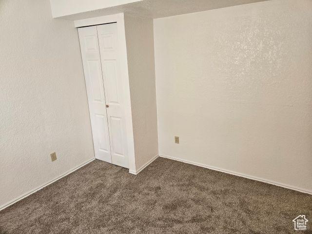 5063 S 2825 W, Roy, UT 84067 - unfurnished bedroom with a closet, dark carpet, and a textured wall