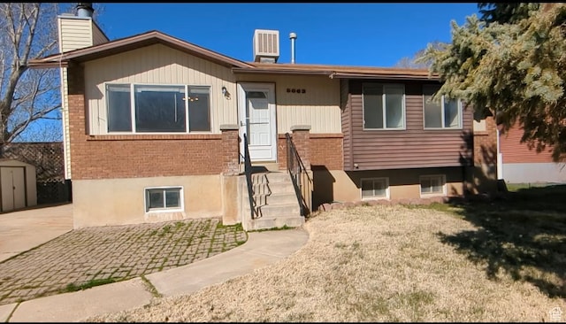 5063 S 2825 W, Roy, UT 84067 - view of front of house with central air condition unit, a chimney, a front yard, brick siding, and an outbuilding