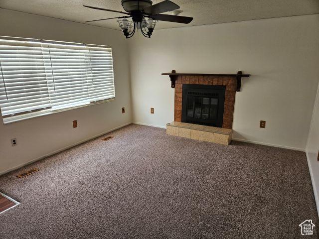 5063 S 2825 W, Roy, UT 84067 - unfurnished living room featuring a ceiling fan, carpet floors, a fireplace, and visible vents