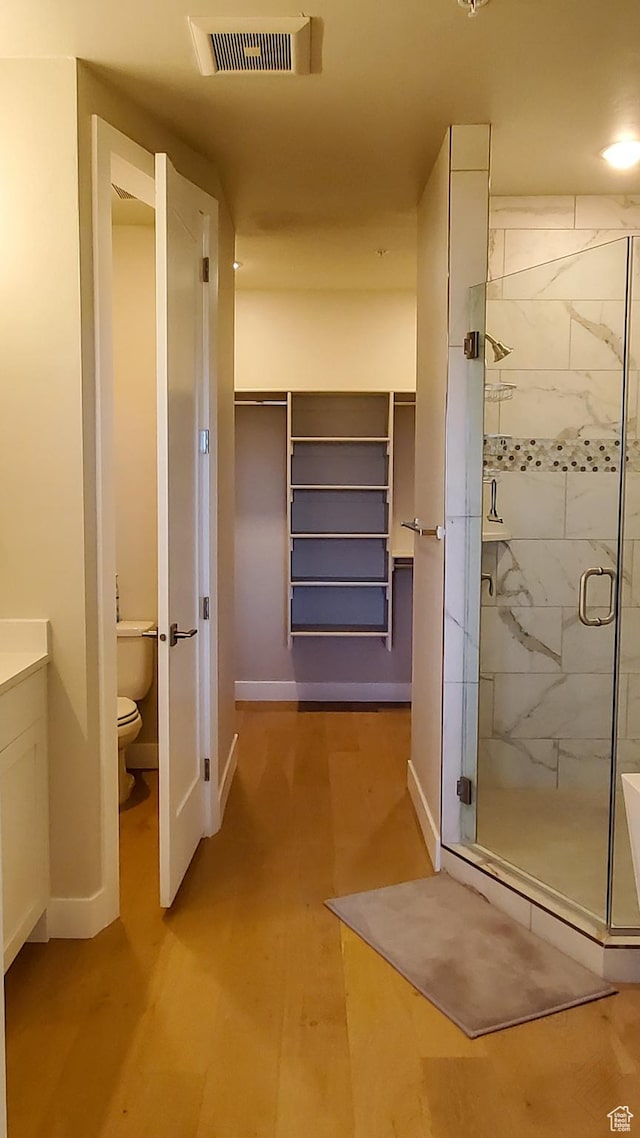 full bath with wood finished floors, baseboards, visible vents, a stall shower, and toilet
