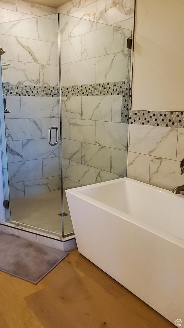 bathroom featuring a freestanding tub, wood finished floors, and a stall shower
