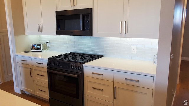 kitchen with tasteful backsplash, white cabinets, light countertops, and range with gas cooktop