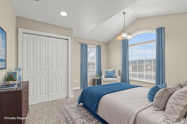 bedroom featuring lofted ceiling, a textured ceiling, a closet, carpet floors, and baseboards