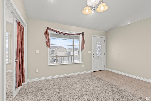 carpeted foyer with tile patterned flooring, an inviting chandelier, baseboards, and lofted ceiling