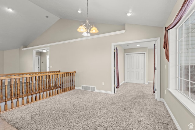 interior space with visible vents, lofted ceiling, an inviting chandelier, and carpet flooring