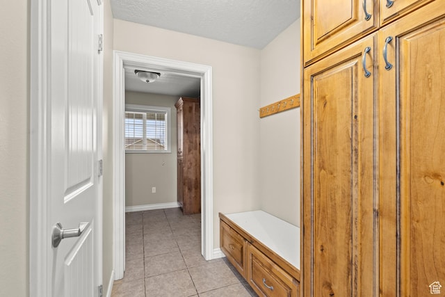 mudroom with light tile patterned floors, a textured ceiling, and baseboards