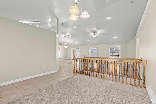 tiled empty room with carpet, vaulted ceiling, ceiling fan with notable chandelier, and baseboards