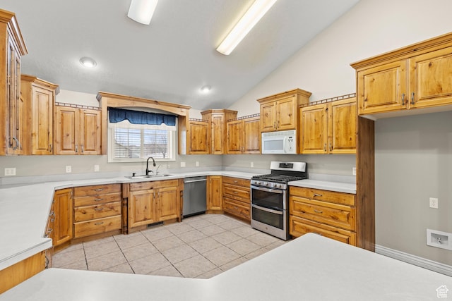 kitchen with light tile patterned floors, a sink, vaulted ceiling, light countertops, and appliances with stainless steel finishes