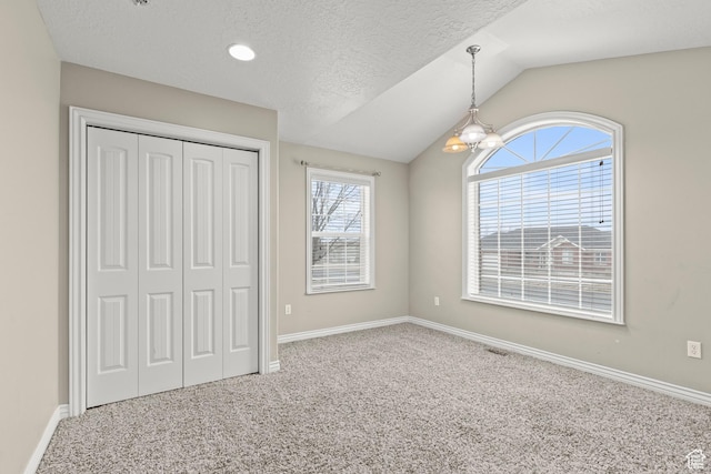 unfurnished bedroom featuring a textured ceiling, a closet, carpet, baseboards, and vaulted ceiling