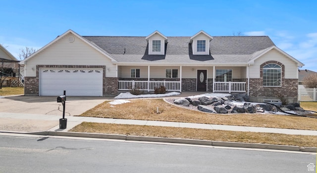cape cod home with a garage, covered porch, brick siding, and driveway