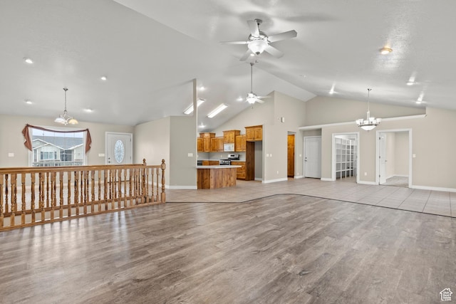 living room featuring light wood finished floors, ceiling fan with notable chandelier, high vaulted ceiling, and baseboards