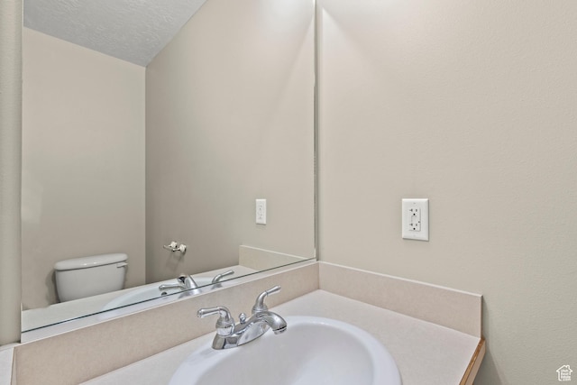 bathroom featuring toilet, a textured ceiling, and vanity