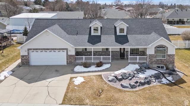 cape cod home featuring a porch, an attached garage, driveway, and a shingled roof